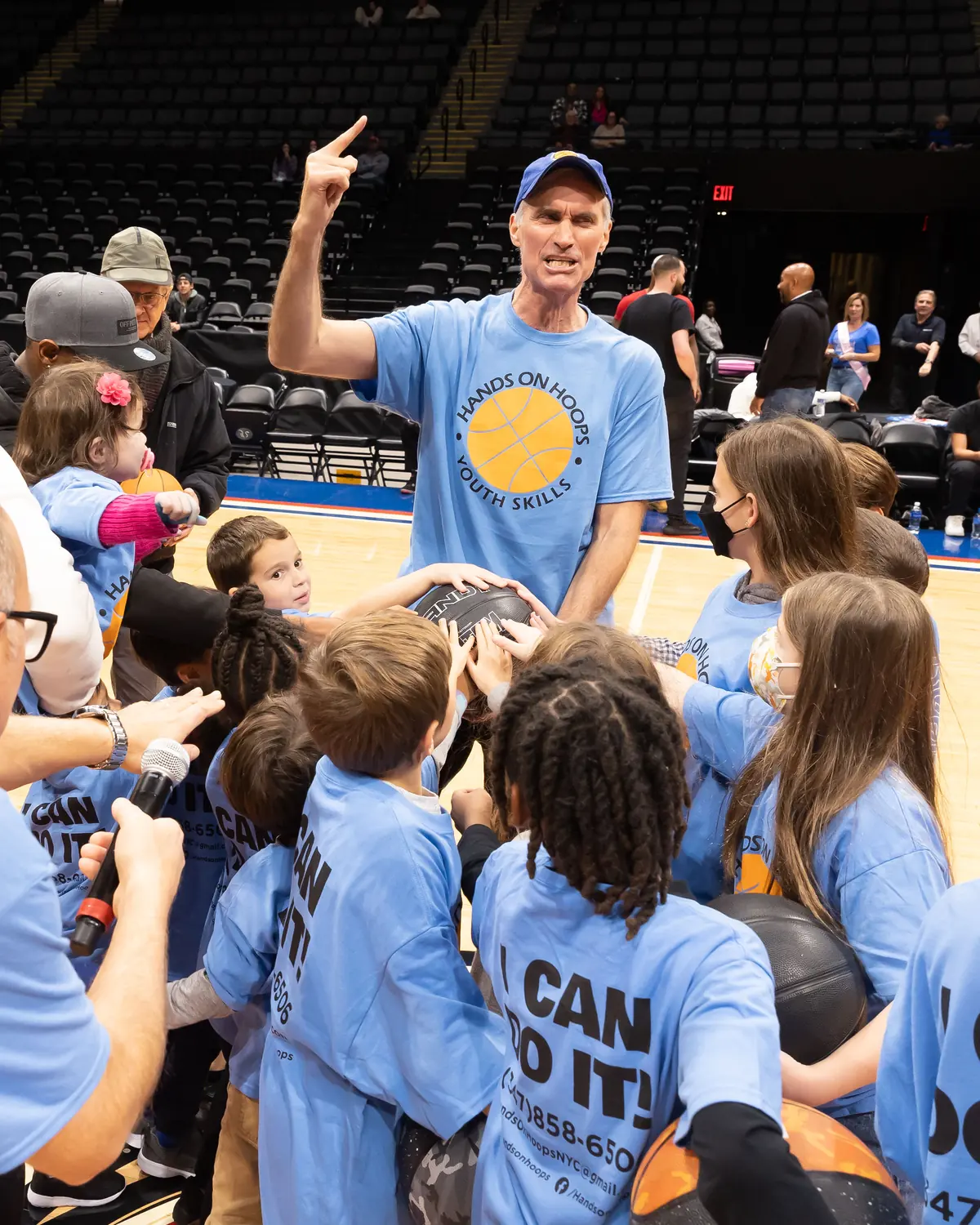 Coach pointing up with a group of kids in I Can Do It shirts
